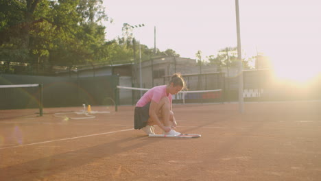 Female-tennis-player-on-the-court-tying-her-shoelaces